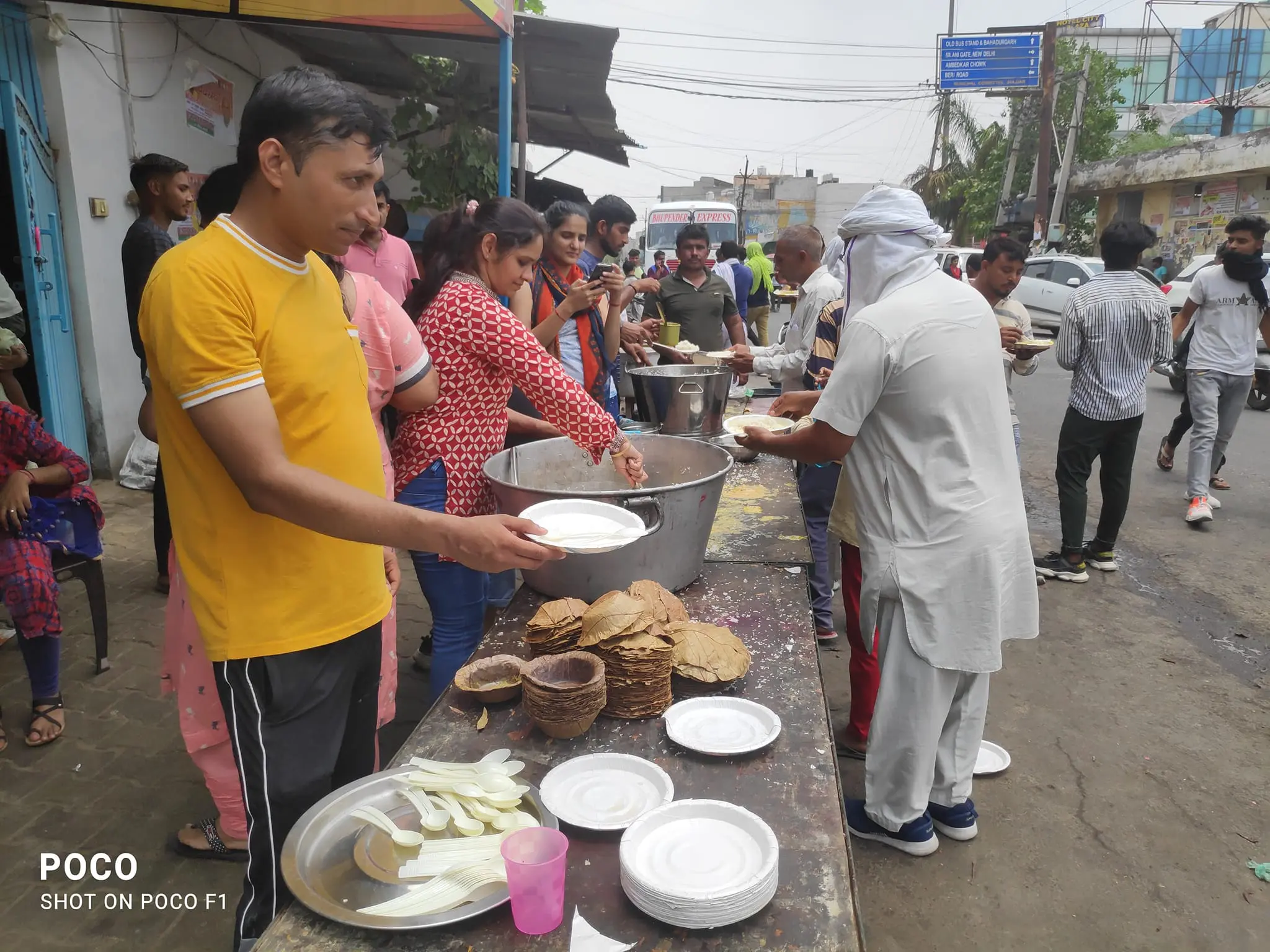 A group of people standing around plates on the street.